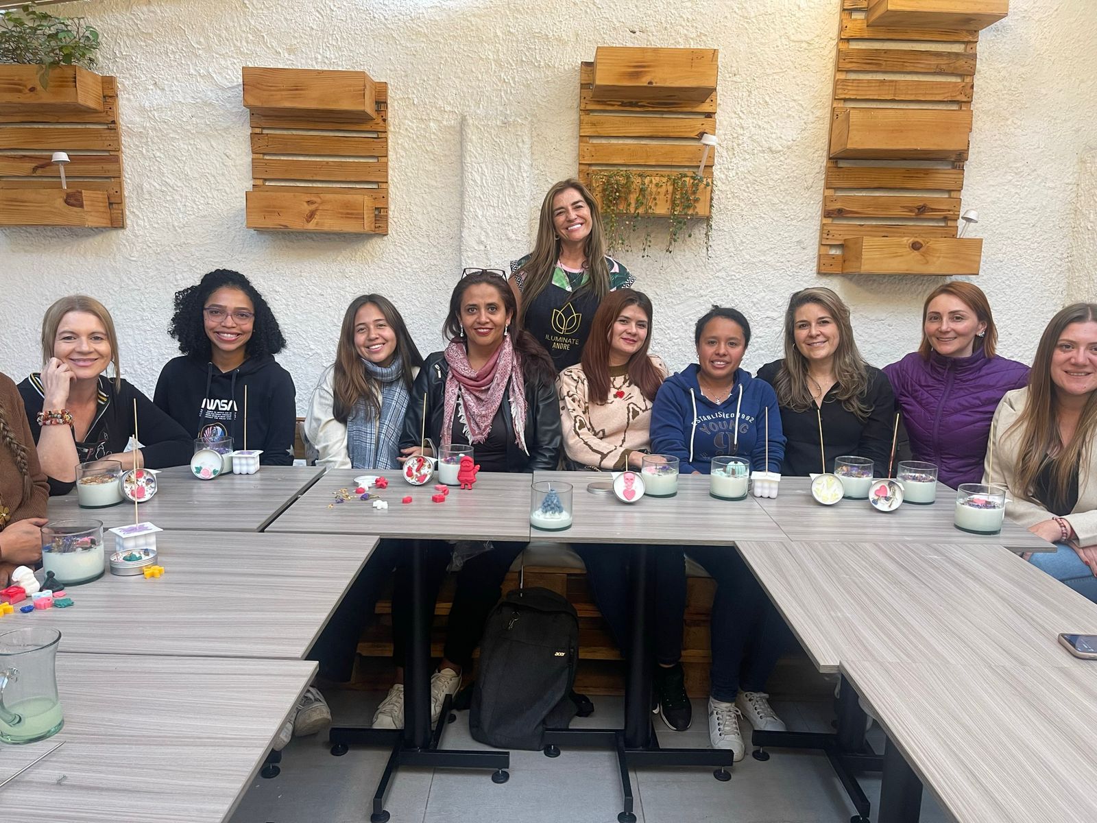 Grupo de mujeres y un niño sonrientes participando en un taller de velas artesanales Iluminate. Sobre Iluminate Studio