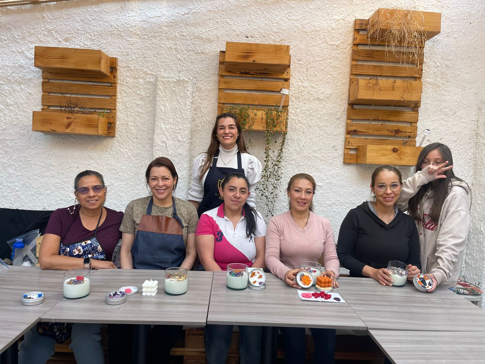 Grupo de mujeres sonrientes mostrando las velas que elaboraron durante un taller artesanal Iluminate Studio Bogotá